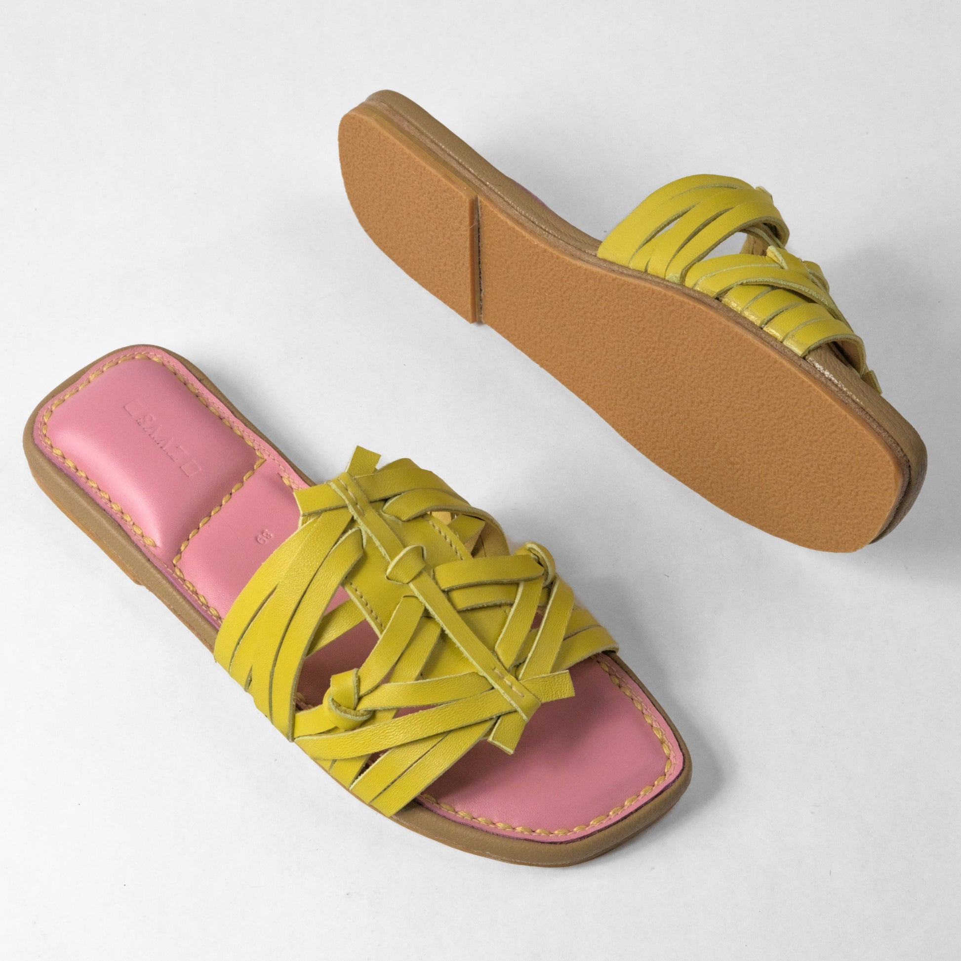 Pair of sandals with pink top and yellow straps on a white background
